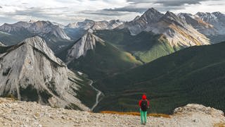 Wanderin blickt vom Gipfel über eine Berglandschaft