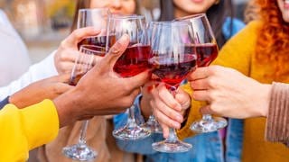 Nahaufnahme von Freunden, die auf einer Straße in der Stadt feiern und mit Wein anstoßen