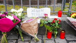 Kerzen, Blumen und ein Blatt Papier mit der Aufschrift „Gegen Terror“ stehen am Tatort auf dem Marktplatz.