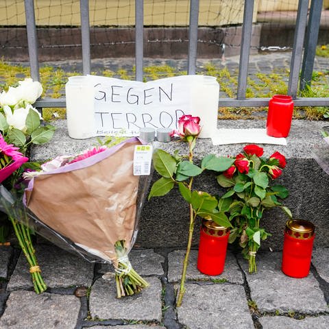 Kerzen, Blumen und ein Blatt Papier mit der Aufschrift „Gegen Terror“ stehen am Tatort auf dem Marktplatz.
