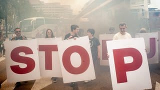 Im Hafen von Barcelona protestieren Menschen gegen Kreuzfahrtschiffe und Massentourismus