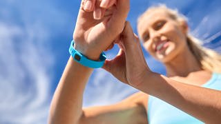 sport, technology and healthy lifestyle concept - close up of happy smiling young woman with fitness tracker outdoors