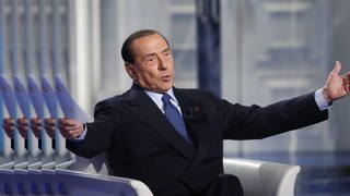 Silvio Berlusconi mit ausgebreitetenArmen als Gast der TV-Show "Porta a Porta" (2019)