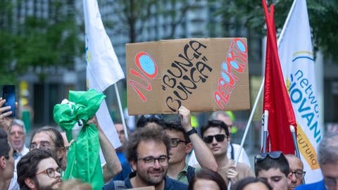 Leute protestieren in Mailand vor dem Sitz der Region Lombardei. Ein Mann hält ein Plakat, worauf steht "No Bunga-Bunga Flughafen "