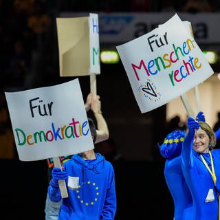 Am von den Rhein-Neckar Löwen ausgerufenen Tag der Vielfalt für Demokratie halten Demonstranten vor dem Anpfiff bunte Schilder hoch