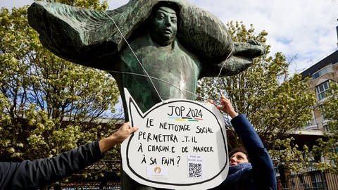 Das Kollektiv „le revers de la médaille" protestiert gegen die „soziale Säuberung" durch die Straßen von Paris. Sie befürchten, dass sich die Olympischen und Paraolympische Spiele negativ auf die Bedürftigen auswirken werden. Auf dem Plakat:  „wird die soziale Säuberung, den Hunger jedes stillen?"
