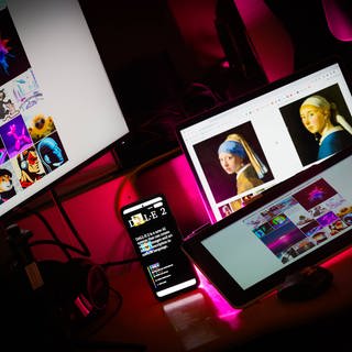 Verschiedene KI-Bildgeneratoren auf Desktop und Handydisplay