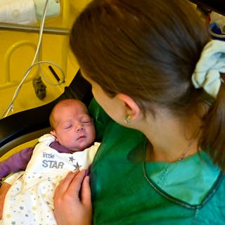 Gesundheitspflegerin kuemmert sich um ein Neugeborenes.