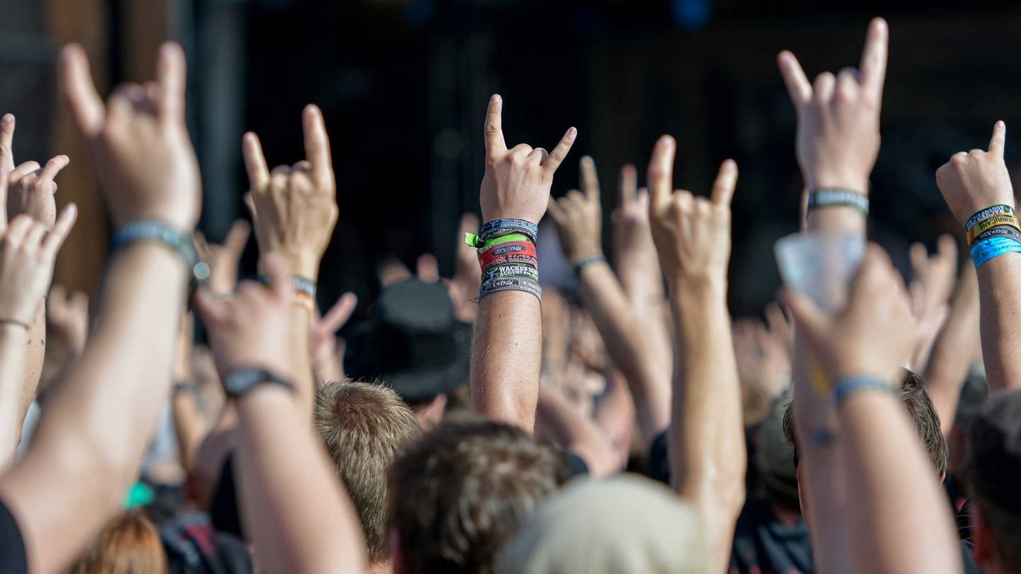 Metal-Fans feiern am 05.08.2016 in Wackenauf dem Festivalgelände des Wacken Open Air mit dem Metal-Gruß, der sogenannten Pommesgabel.