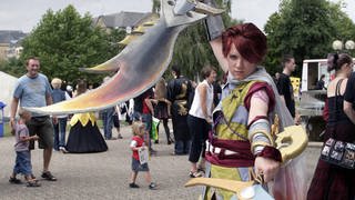 Animagic 2005: Cosplayende Person posiert in einem Fantasy-Kostüm mit zwei Schwertern.