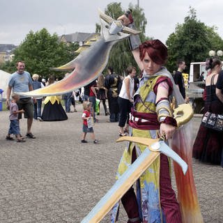 Animagic 2005: Cosplayende Person posiert in einem Fantasy-Kostüm mit zwei Schwertern.