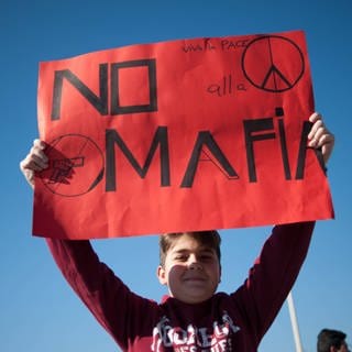 Ein Junge hält beim Marsch zum Gedenken an die Opfer der Mafia ein Schild mit der Aufschrift "No Mafia"