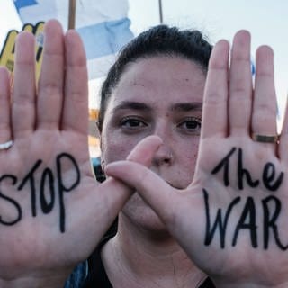 Anti-Kriegs-Demonstrationen in Israel: Eine Frau hält ihre Hände in die Kamera, auf denen "Stop the War" steht 