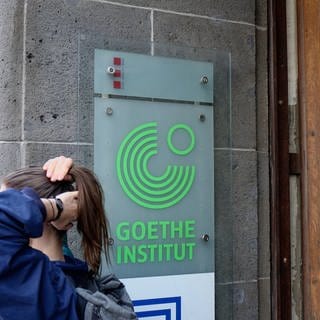 Junge Frau steht vor einem Schild mit Schriftzug Goethe-Institut