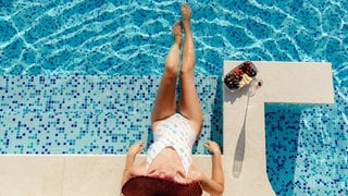 Eine Frau chillt mit Champagner und Früchten am Swimmingpool