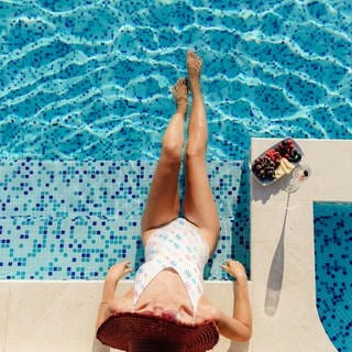 Eine Frau chillt mit Champagner und Früchten am Swimmingpool