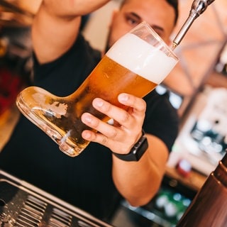 Barkeeper faß Bier vom Fass im Bierglaskoffer. Symbolfoto