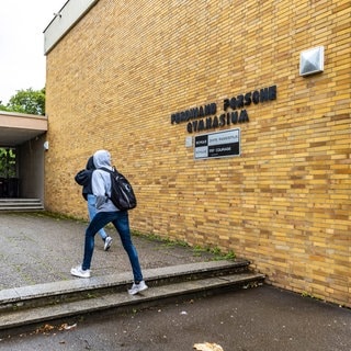 Ferdinand-Porsche-Gymnasium Stuttgart-Zuffenhausen. Schüler am Eingang vor Namensschild der Schule. Unter dem Namen prangt ein Schild mit der Aufschrift: Schule ohne Rassismus. Schule mit Courage. 