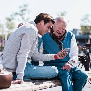 Ein Enkel zeigt seinem Großvater sein Smartphone