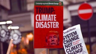 A protester holds a placard describing the election of Donald Trump as a 'climate disaster' during the demonstration. 