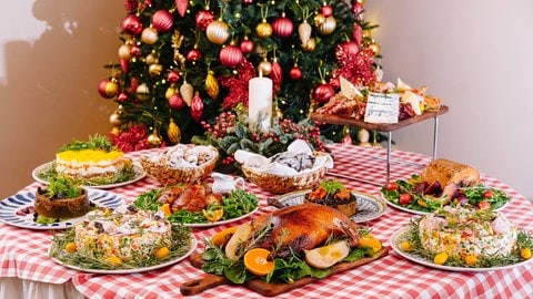 Reich gedeckter Tisch mit Weihnachtsbaum im Hintergrund