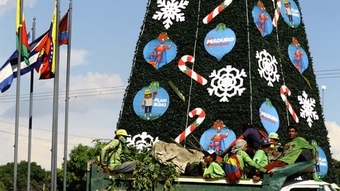 Straßenreinigiger vor einem großem Weihnachtsbaum in Caracas im Oktober 