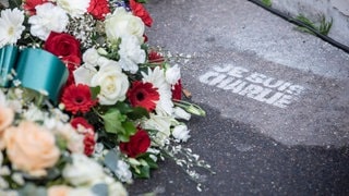 Blumengesteck auf der Straße neben "Je suis Charlie"