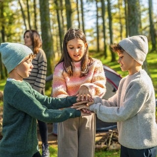 Drei Geschwister spielen im Wald