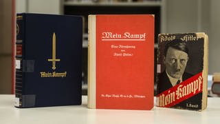 Drei Ausgaben von Adolf Hitlers "Mein Kampf", eine JubilÃ¤umsausgabe zu Hitlers Geburtstag aus dem Jahr 1939 (l-r), die Erstausgabe von 1925 und eine Taschenbuchausgabe von 1933 sind am 03.12.2015 in den RÃ¤umen vom Institut fÃ¼r Zeitgeschichte in MÃ¼nchen (Bayern) zu sehen.
