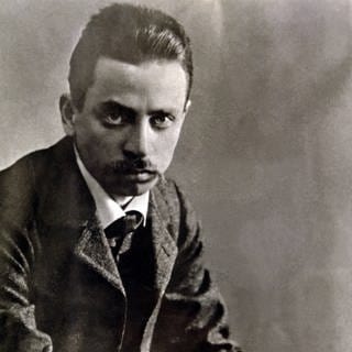 Eine Porträtfotografie des Schriftstellers Rainer-Maria Rilke, der ernst in die Kamera schaut