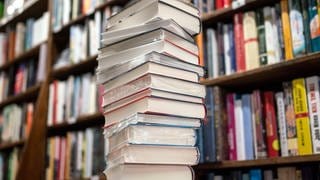 Ein Stapel Bücher liegt auf einem Verkaufstisch in einer Buchhandlung. Am 20. August 2024 werden die 20 Titel der Longlist des Deutschen Buchpreises bekannt gegeben.