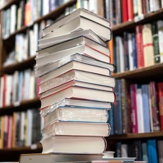 Ein Stapel Bücher liegt auf einem Verkaufstisch in einer Buchhandlung. Am 20. August 2024 werden die 20 Titel der Longlist des Deutschen Buchpreises bekannt gegeben.