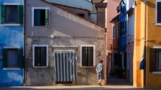 Frau läuft vor einem Haus in eine Gasse