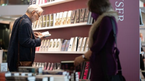 Besucher schauen sich auf der Frankfurter Buchmesse am Stand des Carl Hanser Verlags Bücher an. 