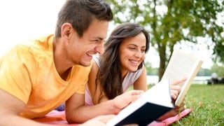 Ein junges Paar liest in einem Park in ihren Büchern.