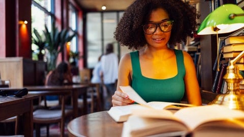 Frau sitzt im Café und liest ein Buch