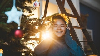 junge Frau mit Kopfhören vor Weihnachtsbaum