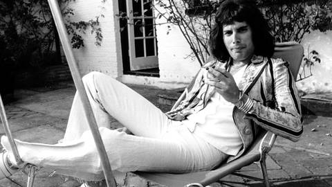 Freddie Mercury mit langen Haaren auf einem Liegestuhl