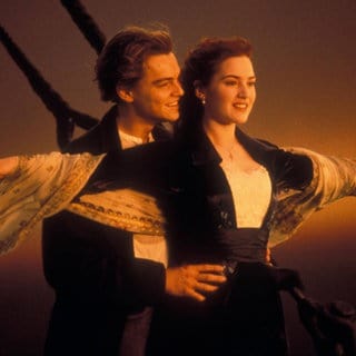 Ein Filmstill aus "Titanic" (1997): Jack (Leonardo DiCaprio) und Rose (Kate Winslet) stehen im Sonnenuntergang am Bug der Titanic