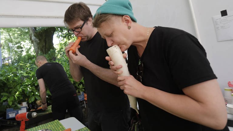Zwei Mitglieder des Wiener Gemüseorchesters probieren die selbstgebauten Instrumente aus Rettich und Karotte aus