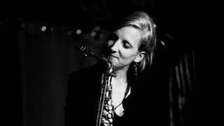 JUnge Frau mit einem Saxophon vor sich  schwarz-weiß Bild