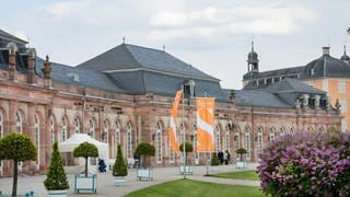 Schwetzinger Schloss mit orangefarbenen Flaggen der Schwetzinger SWR Festspiele davor