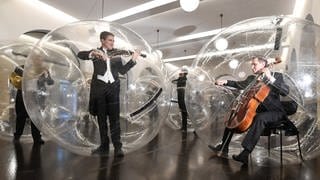 Musiker der Stuttgarter Philharmoniker spielen in Stuttgart während der Kunstaktion "Social Distance Stacks" des Künstlers Florian Mehnert in einem PVC Ball. 