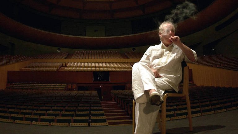 Daniel Barenboim sitzt auf einem Stuhl auf der Bühne und raucht eine Zigarette, 2002