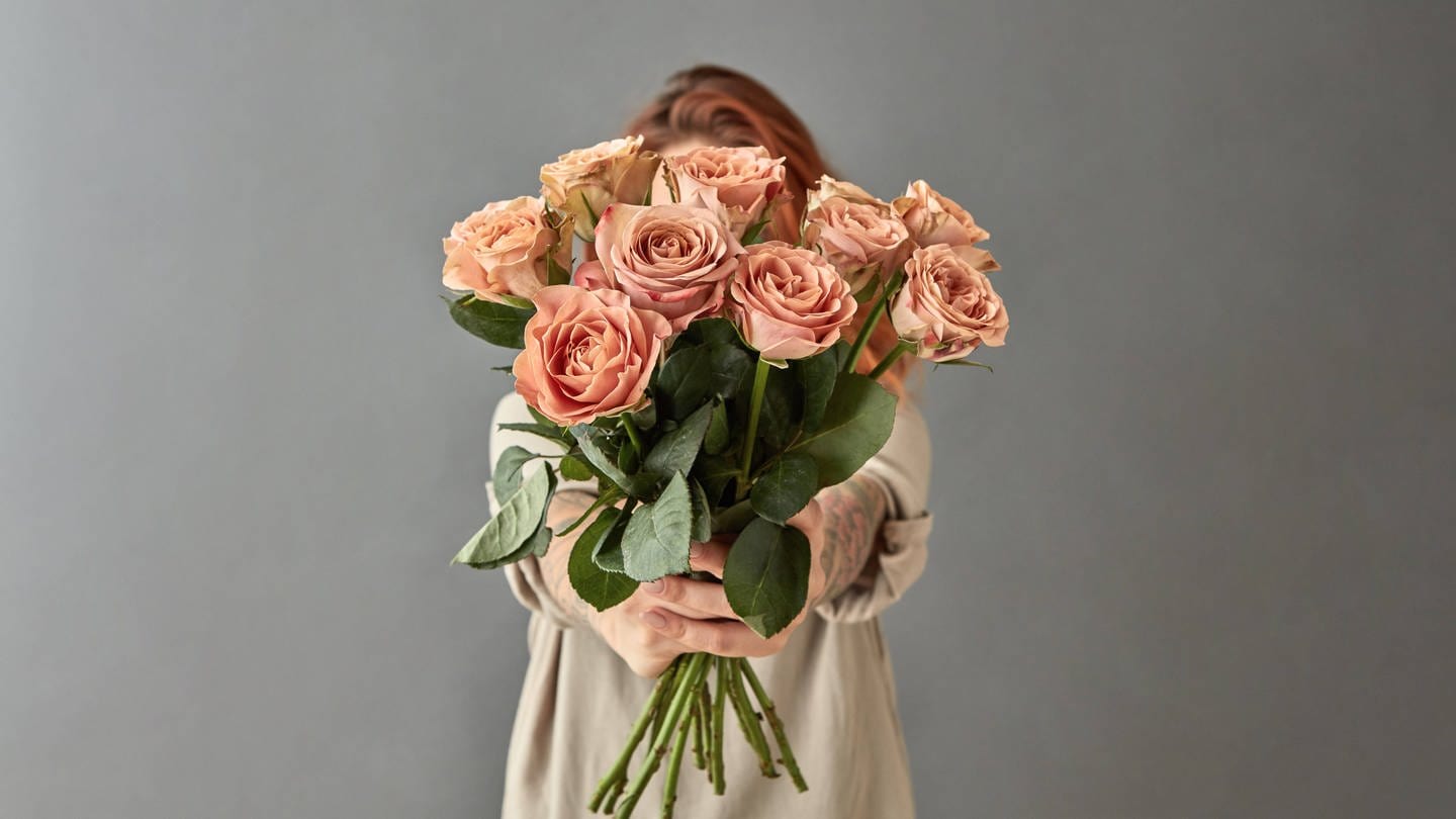 Eine Frau streckt einen Blumenstrauß ins Bild