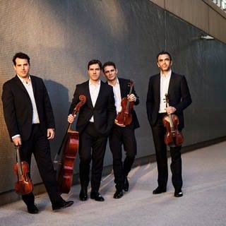 Das Quatuor Modigliani mit Instrumenten an eine Mauer angelehnt