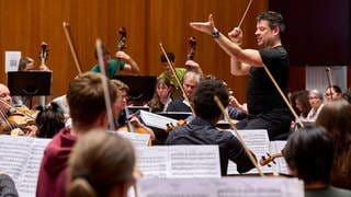 Musiker und Dirigent eines Laienorchesters während einer Proble