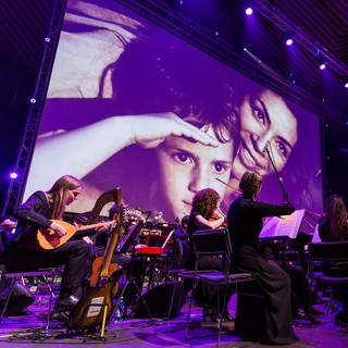 Ein Orchester spielt Filmmusik vor einer Filmleinwand