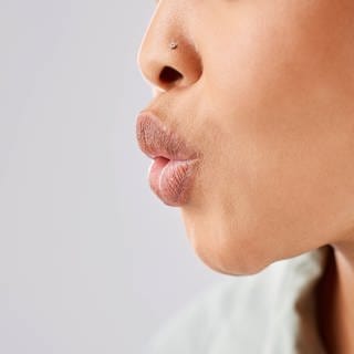 Eine Frau pfeift, man sieht ihre gespitzten Lippen