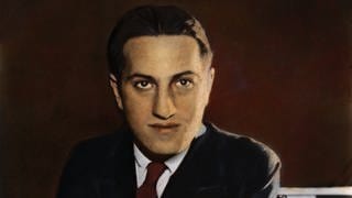 Kolorierte Porträtaufnahme von George Gershwin mit Anzug und zurückpomadierten Haaren.